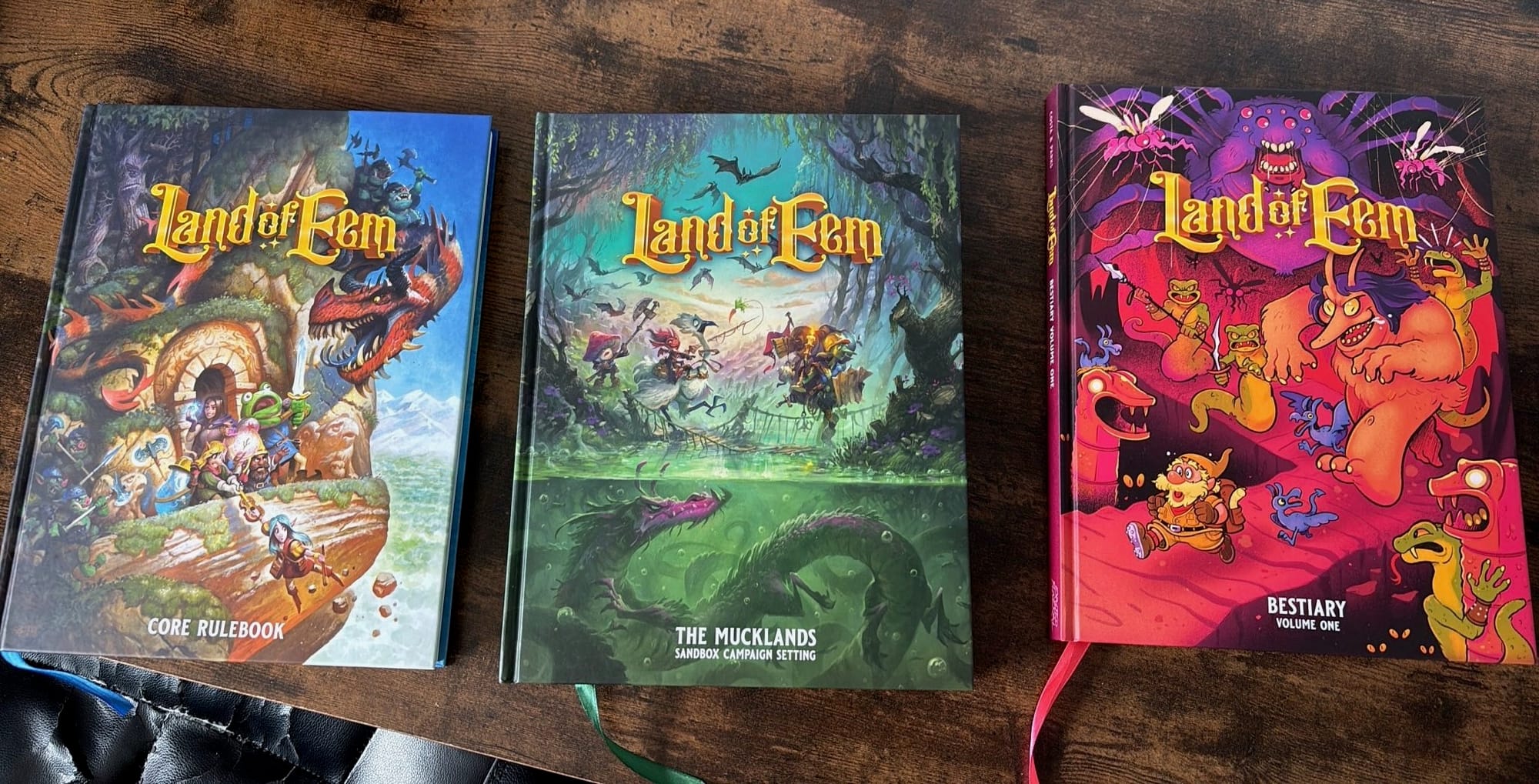 Three books. The core rulebook is an adventuring party circled by monsters, right atop a mountain. The second is a party in a swamp, oblivious to the monsters around them. The 3rd book is a dwarf fleeing big monsters in a dungeon 